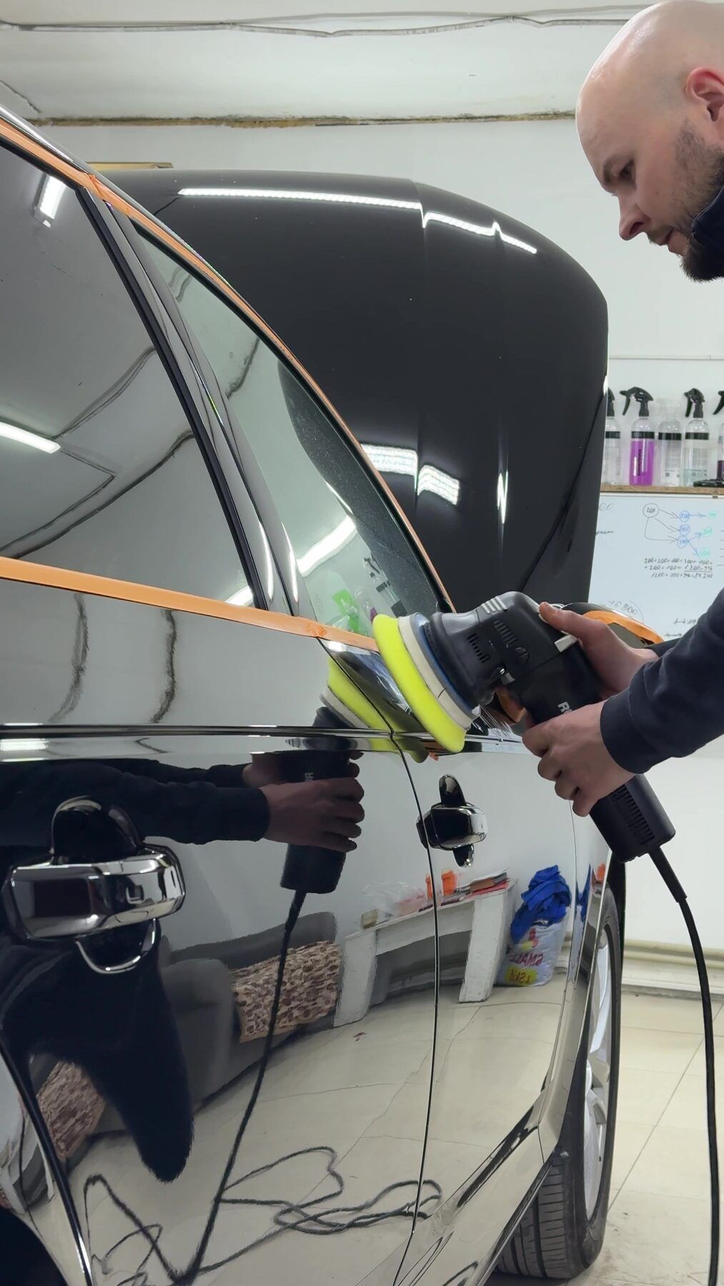 Detailer polishing a black car