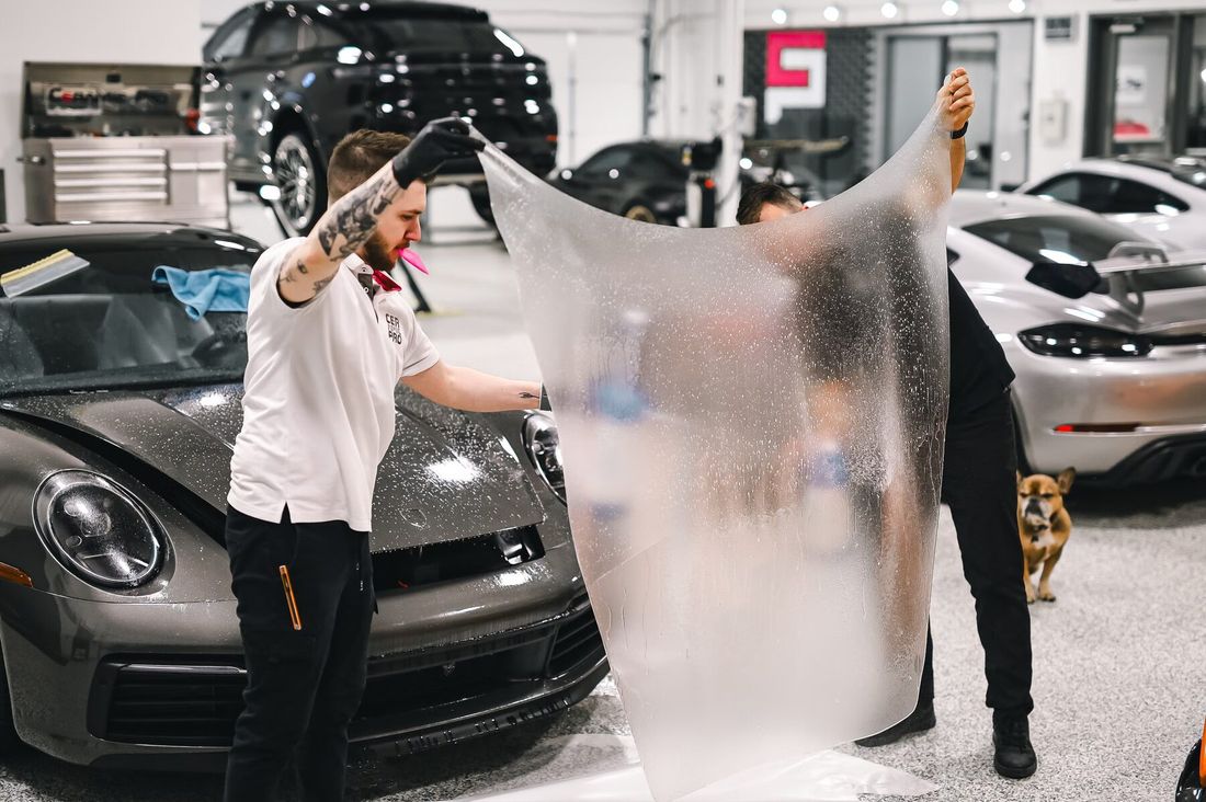 Two technicians laying PPF on a sports car