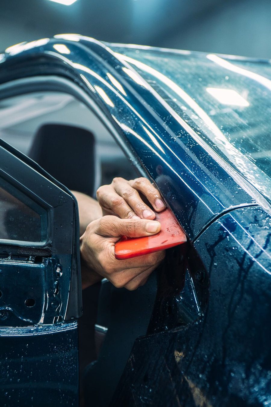 Hand squeegeeing film on a dark car door