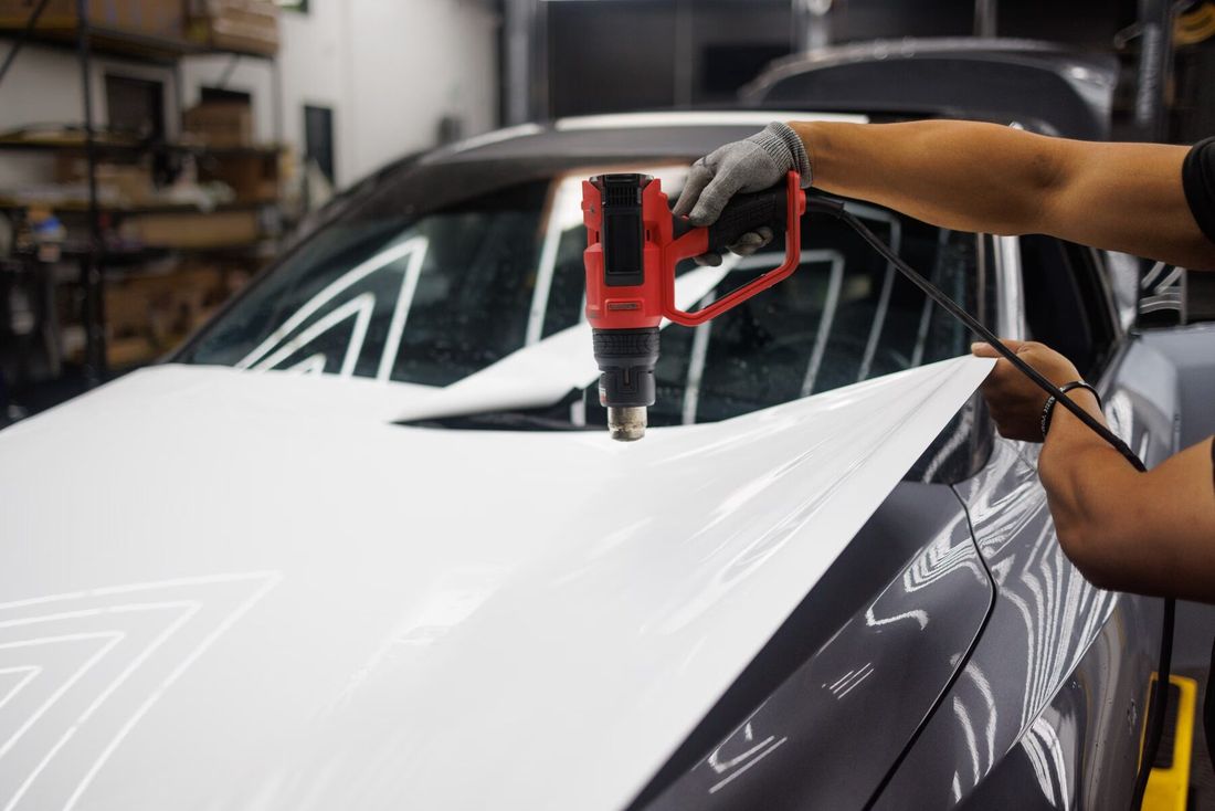 Installer heat-forming white vinyl onto a hood